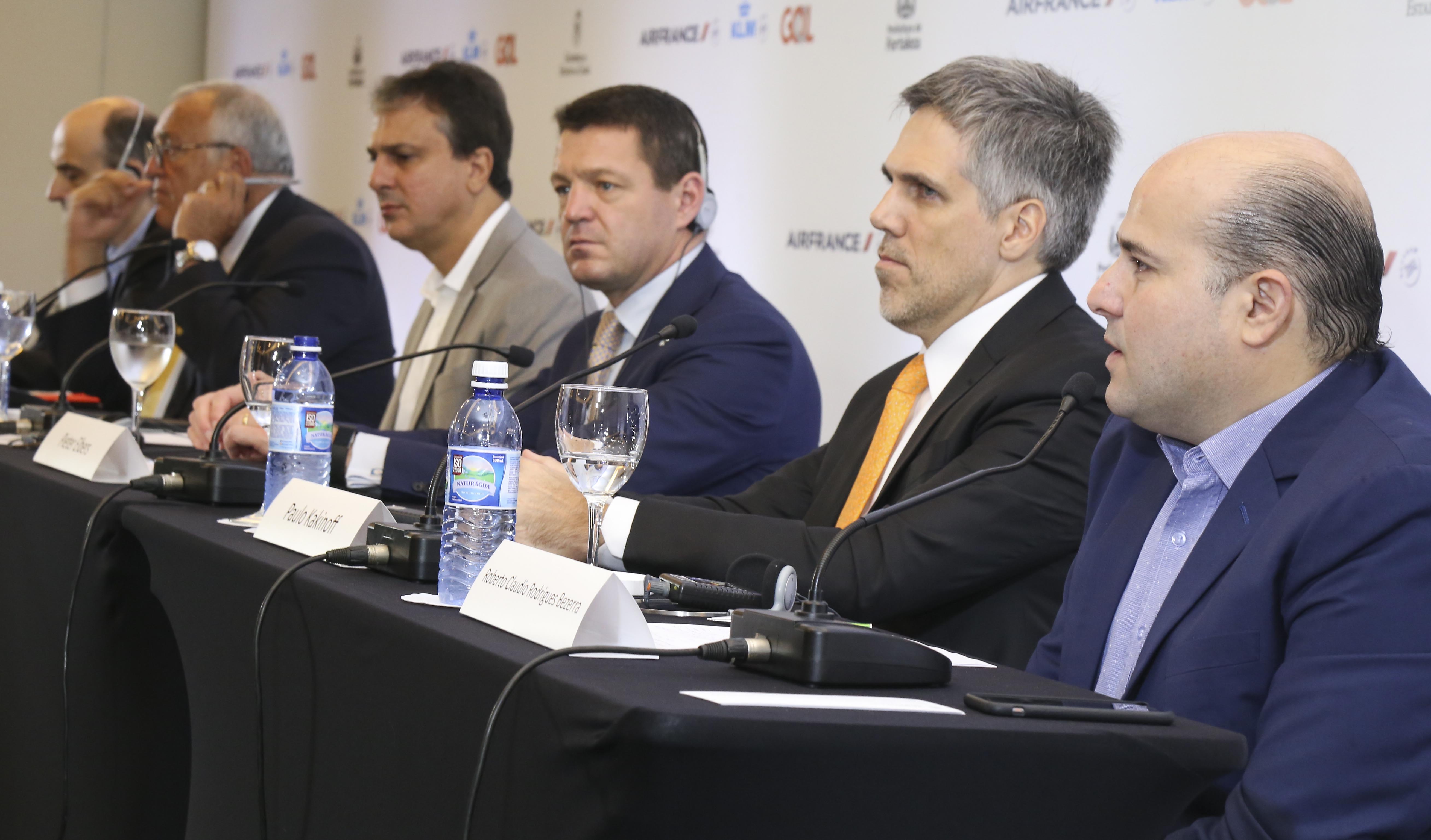 várias pessoas sentadas na mesa da coletiva